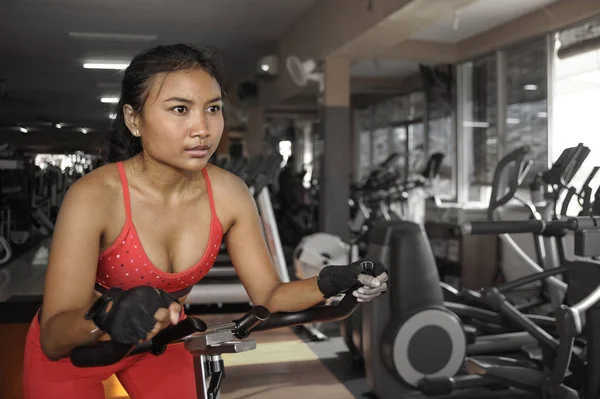 Joven hermosa y sudorosa asiática activa mujer entrenamiento duro ciclismo y montar en bicicleta estática entrenamiento en el gimnasio — Foto de Stock