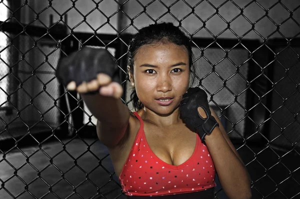 Sexy Asian fighter woman in fighting gloves and sport clothes inside MMA cage posing cool — Stock Photo, Image