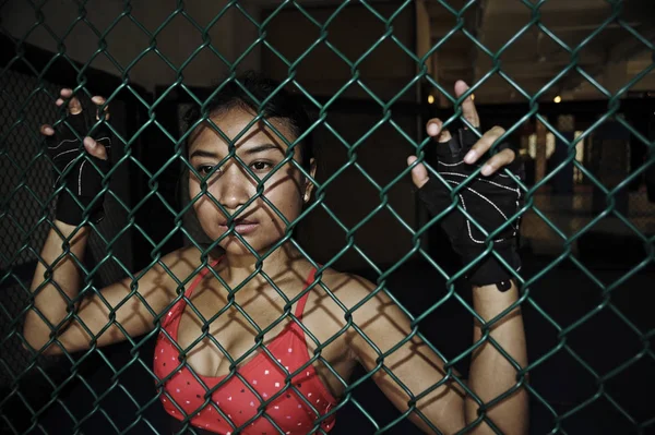 Femeie frumoasă și sexy luptător asiatic în mănuși de luptă și haine sportive în interiorul cuștii MMA care prezintă cool — Fotografie, imagine de stoc