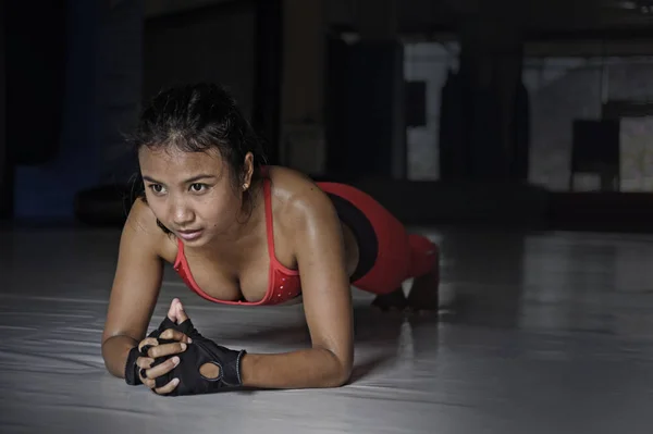 Сексуальная потная азиатка в спортивной одежде лежит на доске на полу спортзала додзё в тяжелой тренировке фитнес-тренировки — стоковое фото