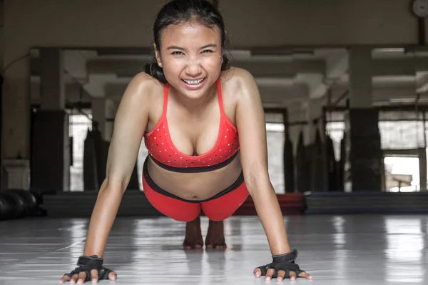 Sexy sweaty Asian woman in sport clothes doing push ups  on gym dojo floor smiling in hard training fitness workout — Stock Photo, Image