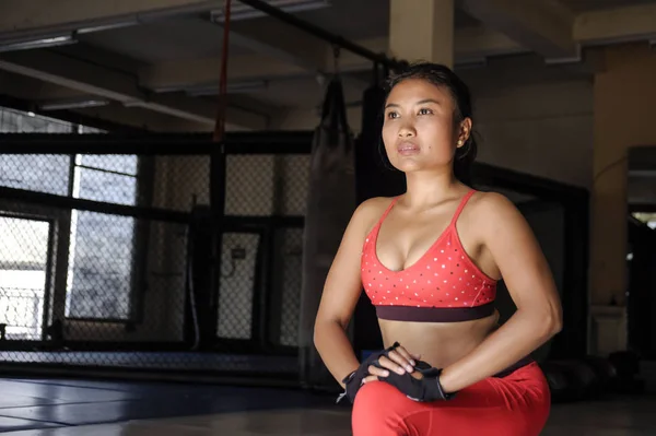 Expresión de la cara concentrada de la joven mujer asiática sudorosa en ropa deportiva estiramiento piernas relajantes músculos en el gimnasio — Foto de Stock