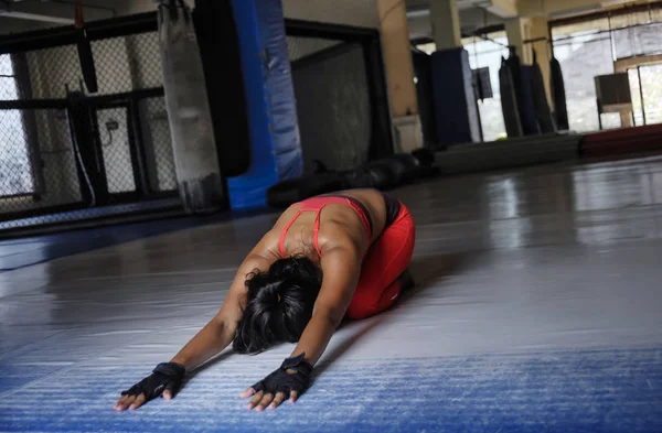 Молодая потная азиатка в спортивной одежде растягивается назад и спинной хребет на полу спортзала додзё в тяжелой тренировки — стоковое фото