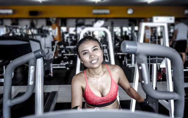 Sexy y sudorosa mujer asiática entrenando duro en el gimnasio usando equipo de máquina de pedaleo elíptico en entrenamiento intenso — Foto de Stock