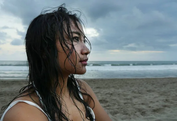 Young beautiful Asian girl with wet hair at sunset beach looking in the distance thoughtful and pensive — Stock Photo, Image