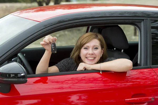 Mulher atraente sorrindo orgulhoso sentado no assento do motorista segurando e mostrando chave do carro na compra de automóveis novos e alugando — Fotografia de Stock