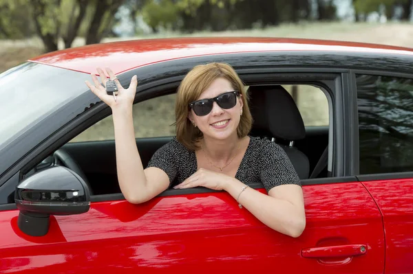 Mulher atraente sorrindo orgulhoso sentado no assento do motorista segurando e mostrando chave do carro na compra de automóveis novos e alugando — Fotografia de Stock