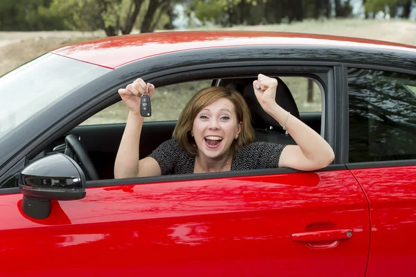 Mujer atractiva sonriendo orgullosa sentada en el asiento del conductor sosteniendo y mostrando la llave del coche en la compra y el alquiler de automóviles nuevos — Foto de Stock