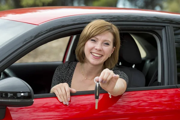 Mulher atraente sorrindo orgulhoso sentado no assento do motorista segurando e mostrando chave do carro na compra de automóveis novos e alugando — Fotografia de Stock