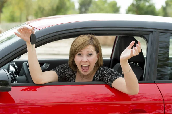 Mujer atractiva sonriendo orgullosa sentada en el asiento del conductor sosteniendo y mostrando la llave del coche en la compra y el alquiler de automóviles nuevos — Foto de Stock