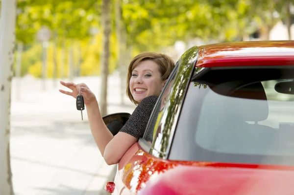 Привлекательная женщина улыбается гордо сидя на водительском сидении, держа и показывая ключи от машины в новых покупках и аренде автомобилей — стоковое фото