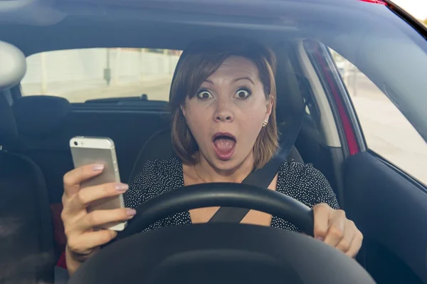 Bela mulher dirigindo carro enquanto mensagens de texto usando telefone celular distraído — Fotografia de Stock