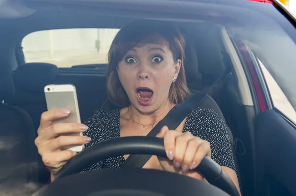 Belle femme conduisant voiture tout en envoyant des SMS en utilisant le téléphone mobile distrait — Photo