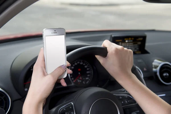 Mão de mulher segurando volante e telefone celular carro de condução enquanto mensagens de texto distraído em risco — Fotografia de Stock