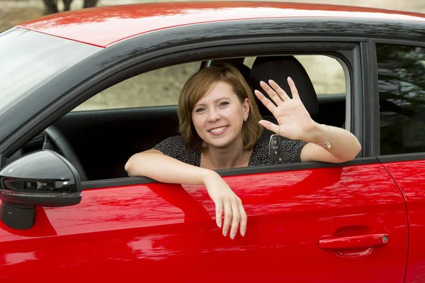 Mulher atraente feliz sentado no assento do motorista sorrindo alegre e orgulhoso acenando Olá de carro novo — Fotografia de Stock