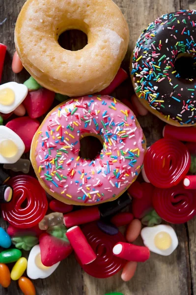 Ungesunde, aber köstliche Gruppe süßer Donut-Kuchen und jede Menge Gummibärchen auf dem Holztisch — Stockfoto