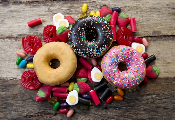 Ungesunde, aber köstliche Gruppe süßer Donut-Kuchen und jede Menge Gummibärchen auf dem Holztisch — Stockfoto