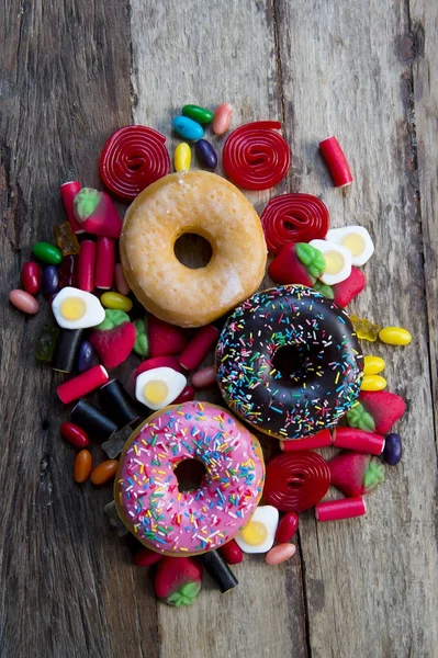 Grupo poco saludable pero delicioso de pasteles de rosquilla de azúcar dulce y un montón de caramelos gomosos en la mesa de madera vintage — Foto de Stock