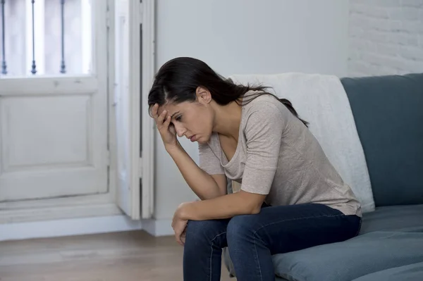 Mujer latina tumbada en casa sentada en el sofá llorando preocupada sufriendo depresión sintiéndose triste —  Fotos de Stock