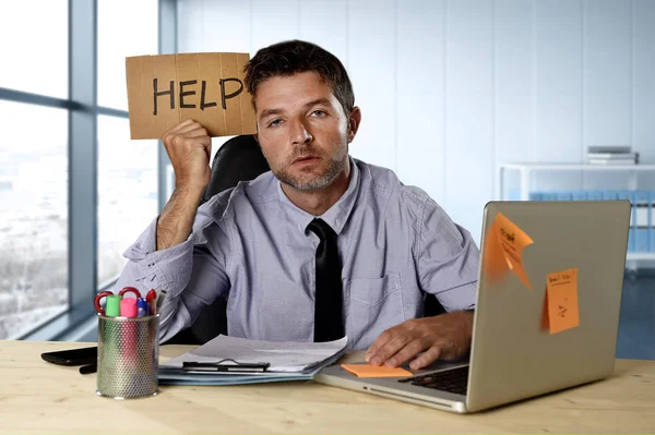 Hombre de negocios que sufre estrés trabajando en el escritorio de la computadora sosteniendo el cartel pidiendo ayuda buscando cansado agotado —  Fotos de Stock