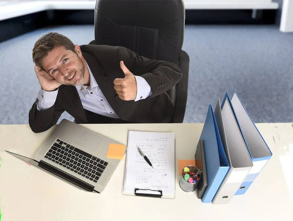 attractive businessman  happy and confident at office with paperwork file working on laptop computer