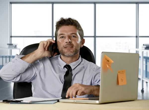 Corporate portret van gelukkig succesvol zakenman in overhemd en stropdas glimlachend op computerbureau met mobiele telefoon — Stockfoto