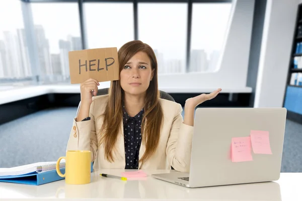 Atractiva mujer de negocios triste y desesperada que sufre estrés en el escritorio de la computadora portátil de la oficina sosteniendo signo de ayuda —  Fotos de Stock