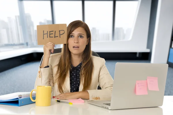 Atractiva mujer de negocios triste y desesperada que sufre estrés en el escritorio de la computadora portátil de la oficina sosteniendo signo de ayuda —  Fotos de Stock