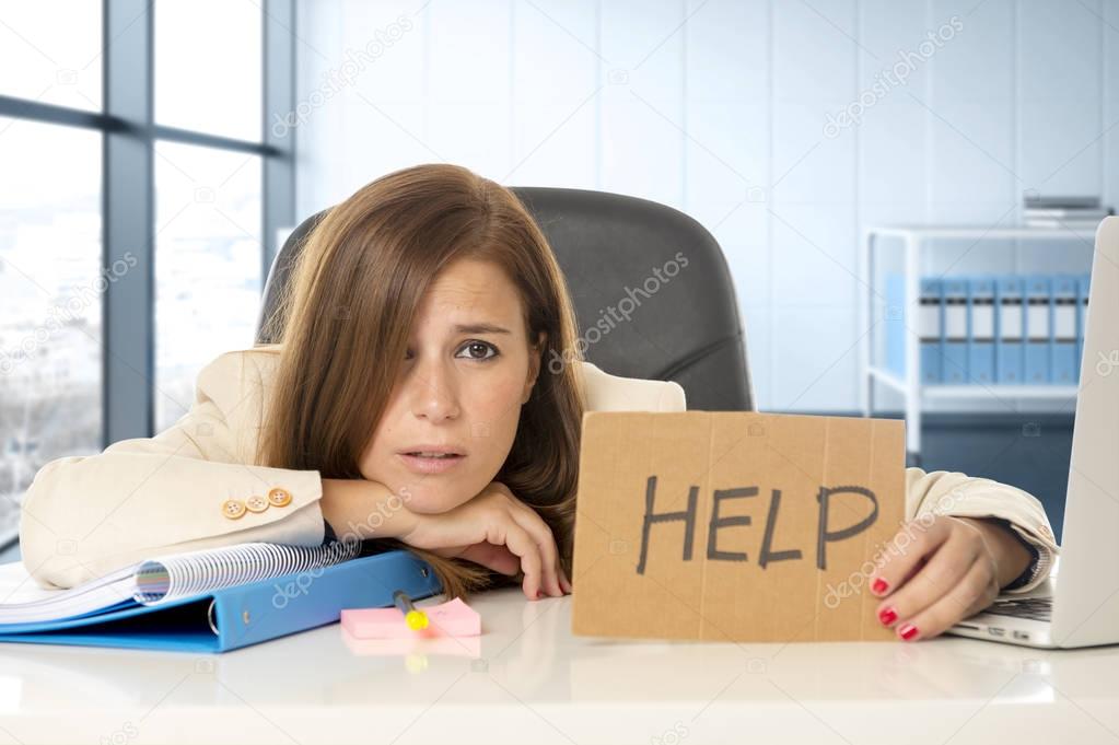 attractive sad and desperate business woman suffering stress at office laptop computer desk holding help sign