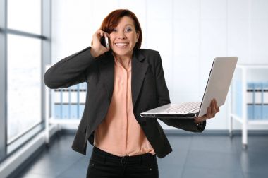 iş kadını cep telefonunda meşgul konuşmak dizüstü bilgisayar ile gülümseyen iş yerinde Kızıl saçlı