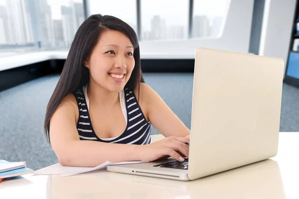 Asiático americano estudiante trabajando con un sonrisa en moderno biblioteca oficina y estudiar para examen con computadora portátil —  Fotos de Stock