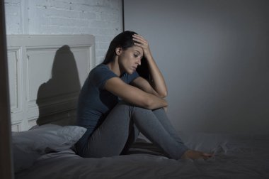 yatağa evde oturan güzel üzgün ve depresyonda Latin kadın acı depresyon sinirli 