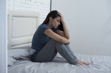 yatağa evde oturan güzel üzgün ve depresyonda Latin kadın acı depresyon sinirli 