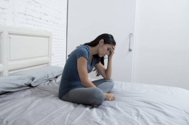 yatağa evde oturan güzel üzgün ve depresyonda Latin kadın acı depresyon sinirli 