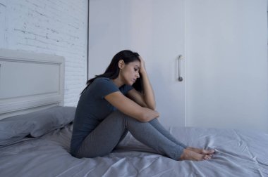 f yatağa evde oturan güzel üzgün ve depresyonda Latin kadın