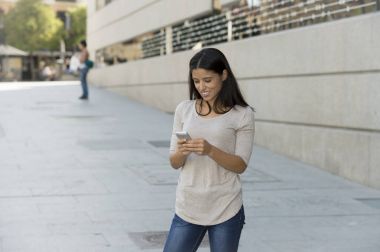Internet üzerinde cep telefonu mesaj kullanarak kentsel sokak şehir arka plan üzerinde genç güzel ve mutlu latin kadın
