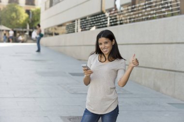 Internet üzerinde cep telefonu mesaj kullanarak kentsel sokak şehir arka plan üzerinde genç güzel ve mutlu latin kadın