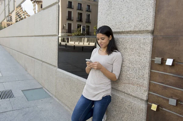 Junge schöne und glückliche lateinische Frau auf städtischen Straße Stadt Hintergrund mit Internet auf Mobiltelefon SMS — Stockfoto