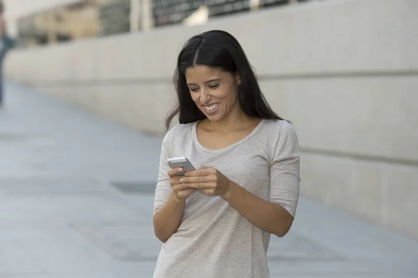 Joven hermosa y feliz mujer latina en la calle urbana fondo de la ciudad utilizando Internet en mensajes de texto de teléfonos móviles — Foto de Stock