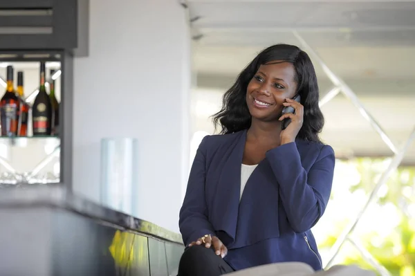 Aantrekkelijk en gelukkig zwarte Afrikaanse Amerikaanse vrouw werken vanuit restaurant bar praten op mobiele telefoon — Stockfoto