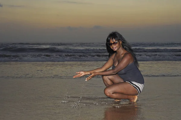 Uvolnil atraktivní afroamerické černá žena chůze na sunset beach se těší vody a písku — Stock fotografie