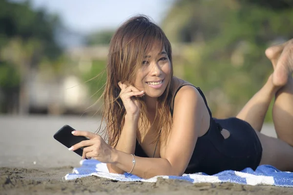 Krásná a šťastná Asijské žena pomocí textových zpráv mobilního telefonu na internetu sociální média usmívající se uvolnil — Stock fotografie