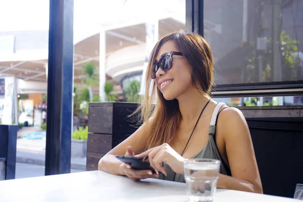 Kaunis ja onnellinen aasialainen nainen käyttää matkapuhelin kutoma sisään — kuvapankkivalokuva