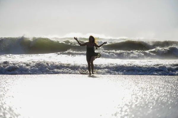 Silhouette of young happy Asian woman relaxed looking at wild sea waves on sunset tropical beach — Stock Photo, Image