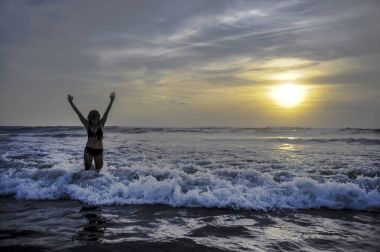 Ufukta deniz manzara günbatımı muhteşem güneş ve dramatik turuncu gökyüzü ile genç aktif kadın