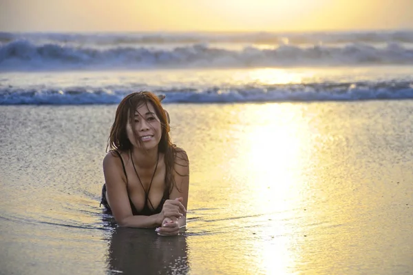 Young Asian woman lying on wet sand on sea landscape sunset horizon with amazing sun — Stock Photo, Image