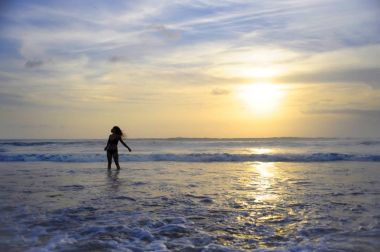 Ufukta deniz manzara günbatımı muhteşem güneş ve dramatik turuncu gökyüzü ile genç aktif kadın