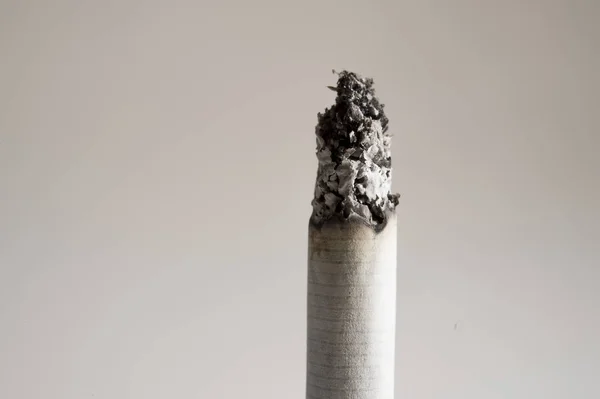 Papieros popiół spalanie na białym tle na jasne tło w niezdrowy nawyk koncepcji uzależnienia od palenia — Zdjęcie stockowe