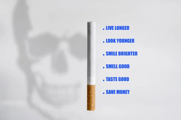 Одна сигарета и тень черепа, представляющие смерть и рак, выделенные на белом фоне в нездоровом курении — стоковое фото