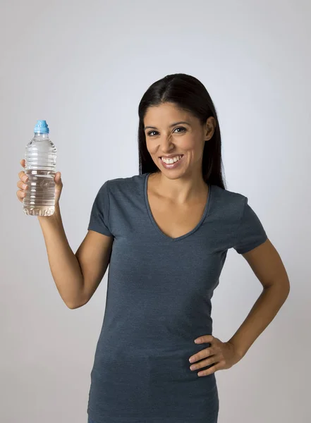 Joven feliz y atractiva mujer latina en ropa casual sosteniendo botella de agua potable sonriendo fresco — Foto de Stock